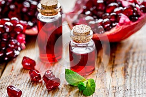 Sliced pomegranate and extract in glass on wooden background