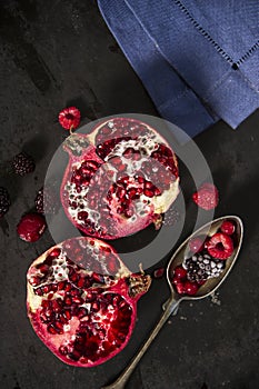 Sliced pomegranate and forest fruits with antique silver spoon.