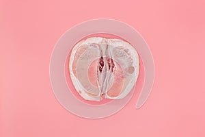 Sliced pomelo on a pink background, the concept of a female vagina