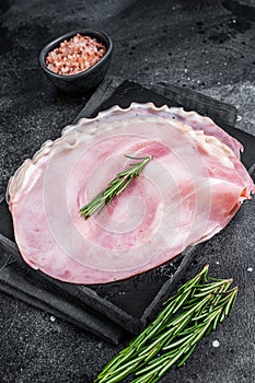 Sliced pork ham on marble board. Black background. Top view