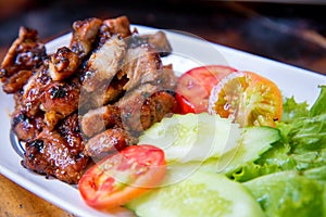 Sliced pork roasted thai style with green leaves salad on rustic plate with cutlery