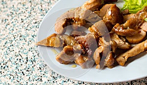 Sliced pork roasted thai style with green leaves salad on rustic plate with cutlery.