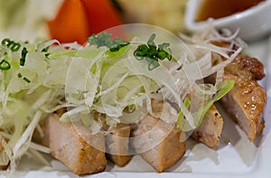 Sliced pork roasted thai style with green leaves salad on rustic plate with cutlery.charcoalboiled pork neck Grill pork