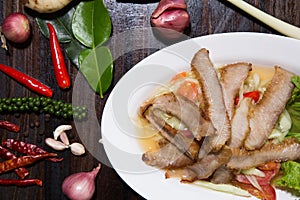 Sliced pork roasted Thai style with green salad on white plate