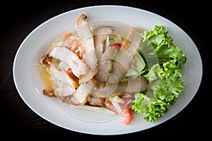 Sliced pork roasted Thai style with green salad on white plate
