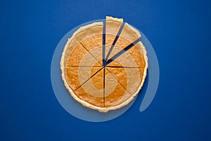 Sliced pumpkin pie isolated on classic blue background. Homemade thanksgiving pie