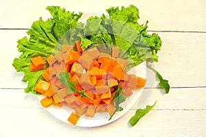 Sliced pumpkin slices on lettuce leaves with pine nuts and arugula. Olive oil, honey and Provencal herbs. Supply of salad in a