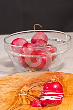 Sliced radish on rare wood plate and bowel of radishes