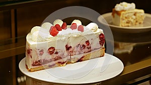 Sliced raspberry cake with butter cream behind the vitrine. Bakery window with cakes. Close up