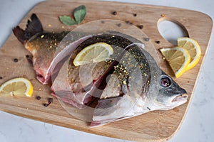 Sliced raw carp with peppers and lemon on cutting board. Cooking fish