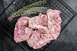 Sliced raw Chicken leg thigh fillet meat ready for cooking with spices. Black background. Top view