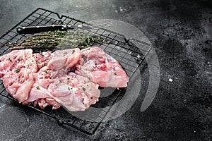 Sliced raw Chicken leg thigh fillet meat ready for cooking with spices. Black background. Top view. Copy space