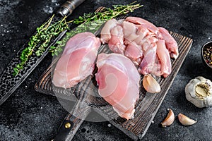 Sliced Raw Chicken thigh fillet on a wooden cutting board. Black background. Top view