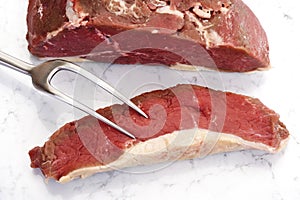 Sliced raw rump steak and meat fork