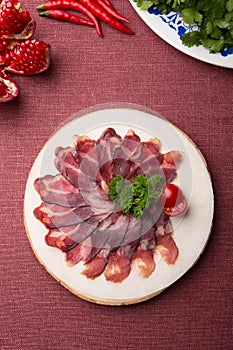 Sliced raw smoked meat served on wooden board
