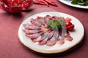 Sliced raw smoked meat served on wooden board