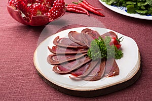 Sliced raw smoked meat served on wooden board