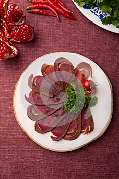 Sliced raw smoked meat served on wooden board