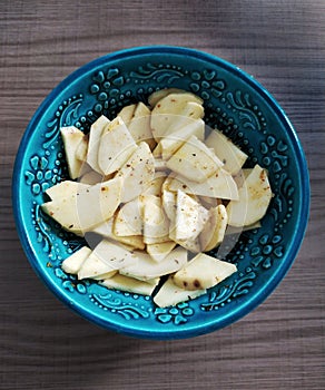 Sliced raw sweet potato chips with seasons inside a bowl decorated in Turkish fashion.