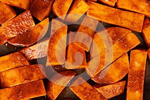 Sliced raw sweet potato with oil and spices on the baking paper, oven pan