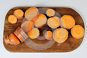 Sliced raw sweet potato with oil and spices on the baking paper, oven pan
