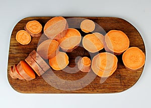 Sliced raw sweet potato with oil and spices on the baking paper, oven pan