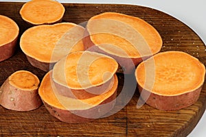 Sliced raw sweet potato with oil and spices on the baking paper, oven pan