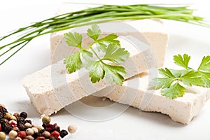 Sliced raw tofu with parsley and spices on white plate