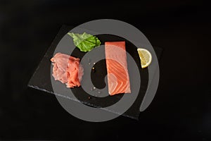 Sliced red fish fillet on the black shale board.