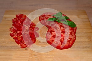Sliced red fresh ripe tomato with basil on the wood background