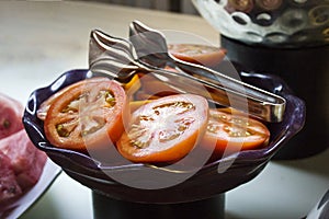 Sliced red large tomatoes on a purple bowl on a table