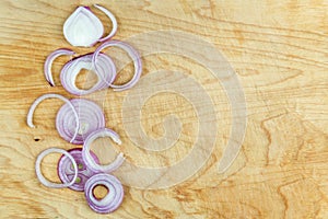 Sliced red onion rings on wooden background top view with space wor text