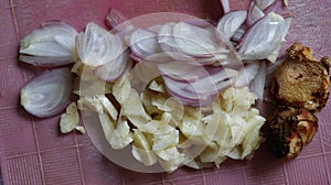 Sliced red onion, white onion, galangal on red kitchen board