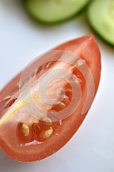 Sliced red tomatoes and green cucumber close-up on a plate