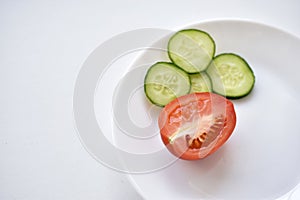 Sliced red tomatoes and green cucumber close-up on a plate