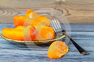 Sliced of a ripe orange persimmon on a saucer