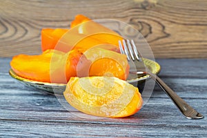 Sliced of a ripe orange persimmon on a saucer