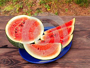 Sliced ripe red watermelon on a blue plate on a wooden table