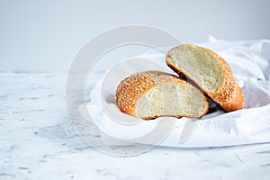 Sliced rolls sprinkled with sesame seeds on a white towel. Home baking and breakfast concept. Copy space for your text