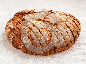 Sliced round loaf of rye bread with an appetizing crispy brown crust on a gray linen tablecloth. Tasty, usefull and nutritious. photo