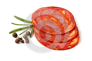 Sliced round pieces of raw-cured Chorizo sausage with rosemary leaf on a white background photo