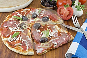 Sliced round pizza with vegetables on a served with cutlery on a