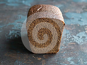 Sliced rye bread on cutting board on dark background. Copy space, close up