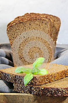Sliced rye bread with leaf basil on cutting board. Whole grain rye bread with seeds