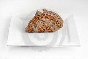 Sliced rye bread on square plate on white background