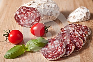 Sliced salami with basilic, cherry tomato on board