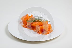 Sliced salmon with basilic beautifully placed on a plate isolated on a white background