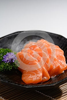 Sliced salmon with parsley leaf in black plate. Japanese food style