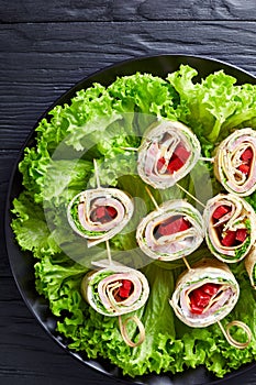 Sliced sandwich wraps on a plate, top view