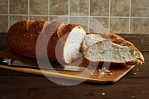 Sliced sesame seed loaf of bread on cutting board